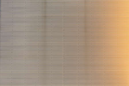 Metal wall facade with a pattern and a sunlight background.の写真素材
