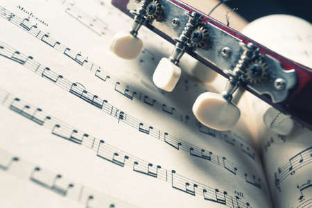 Head and pegs of a guitar on music notes. Vintage colors. Musical instrument.の写真素材