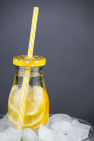 Lemonade in trendy bottle with straw on ice. Copy space to the right. Abstract of summer drink.の写真素材