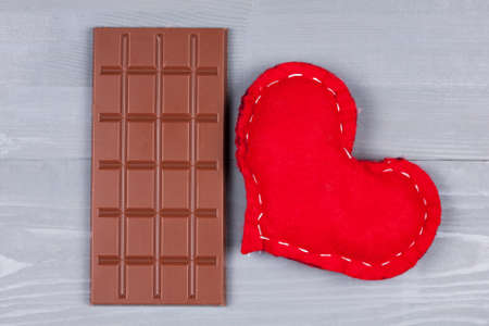 Milk chocolate and red homemade heart on grey natural wooden background.の写真素材
