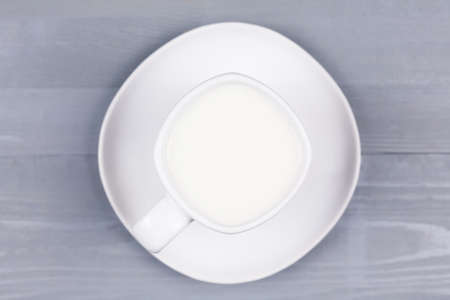 Top view of a white cup of milk on natural grey wood background. Concept of hot drink for autumn fall season.の写真素材
