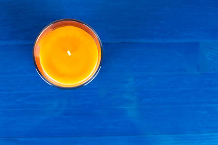 Top view of an orange candle on blue wooden background. Copy space to the right.の写真素材