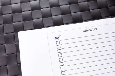 Checklist with check mark ticked on checkered black background.の写真素材