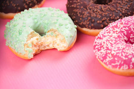 Sweet colorful tasty donuts with icing and sprinkles on pastel pink background.の写真素材
