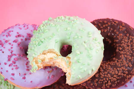 Sweet colorful tasty donuts with icing and sprinkles on pastel pink background.の写真素材