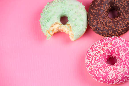 Sweet colorful tasty donuts with icing and sprinkles on pastel pink background.の写真素材