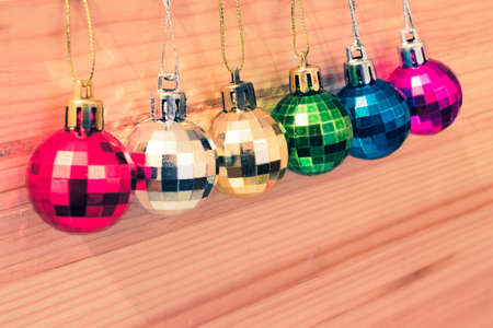 Assortment of colorful christmas tree baubles in a row on natural wooden background. Copy space at the bottom. Vintage colors.の写真素材