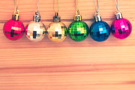 Assortment of colorful christmas tree baubles in a row on natural wooden background. Copy space at the bottom. Vintage colors.の写真素材