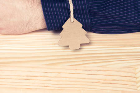 Pine tree shaped label tied with twine to an elegant man or businessman. Natural wooden table. Giving oneself as a present or gift abstract concept. Vintage colors.の写真素材
