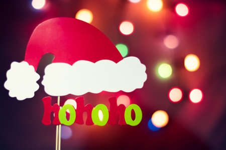Christmas Santa Claus "hohoho" exclamation with colorful tree lights bokeh background with a hat made of photo booth props. Copy space at the top right corner.の写真素材