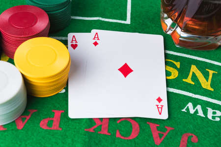 Casino chips and cards on green table. Two aces. Whisky alcoholic drink. Gambling problems abstract concept.の写真素材