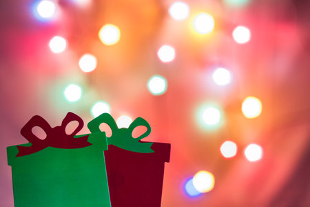 Two red and green christmas presents photo booth props with tree lights bokeh in the background....