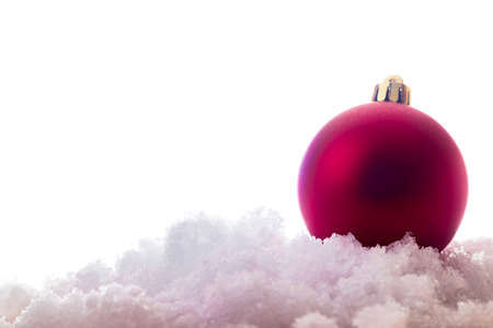 Christmas tree bauble ornament on the snow. Isolated on white background. Copy space to the left.の写真素材