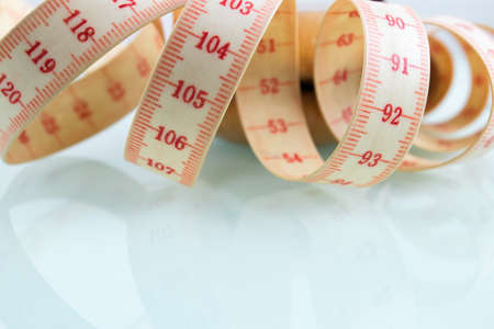 Yo-yo effect in diet concept. Centimeter tape measure. Reflective glass background. Copy space on the bottom.の写真素材