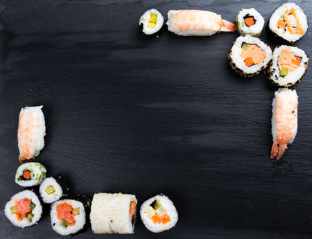 Japanese sushi on black kitchen slate plate. Typical asian cuisine. Maki and nigiri. Frame. Copy space in the center.の写真素材