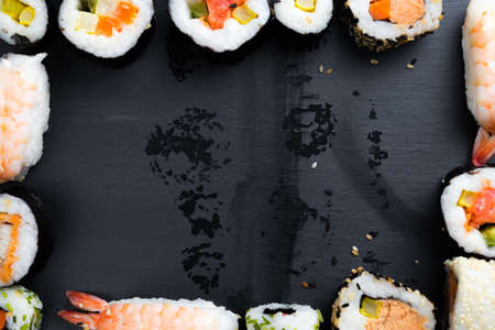Japanese sushi on black kitchen slate plate. Typical asian cuisine. Maki and nigiri. Frame. Copy space in the center. Water drops.の写真素材