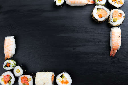 Japanese sushi on black kitchen slate plate. Typical asian cuisine. Maki and nigiri. Frame. Copy space in the center.の写真素材