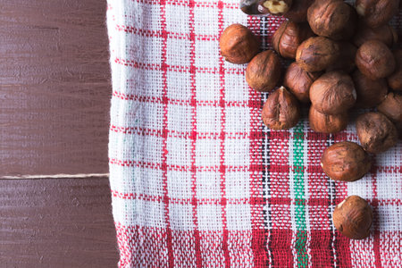 Hazelnuts on a vintage kitchen dishcloth. Brown wooden table. Flat lay top view. Copy space on the...