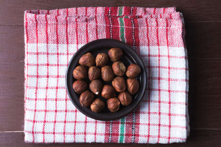 Hazelnuts on a plate with old kitchen dishcloth. Brown natural table. Flat lay top view. Vegetarian food concept.の写真素材