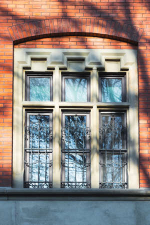 Window in an old building made of red bricks. Rich ornaments. Warm afternoon light during sunset.の写真素材
