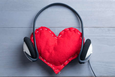 Red homemade heart with headphones on Valentine's Day. Love for music abstract concept.の写真素材