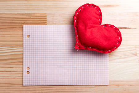 Empty sheet of paper with homemade red heart on a Valentine's Day. Natural wooden table. Copy space.の写真素材