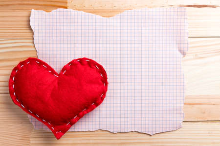 Empty torn sheet of paper with homemade red heart on a Valentine's Day. Natural wooden table. Copy space.の写真素材