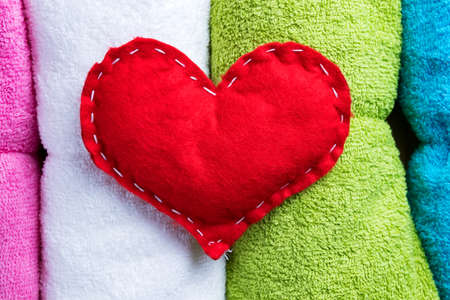 Red homemade heart on colorful towels on Valentine's Day. Romantic spa abstract concept.の写真素材