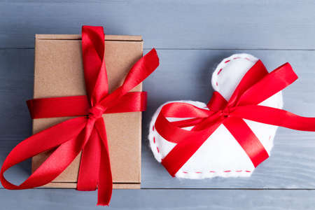 White homemade heart with red ribbon bow and a present or gift on Valentine's Day.の写真素材