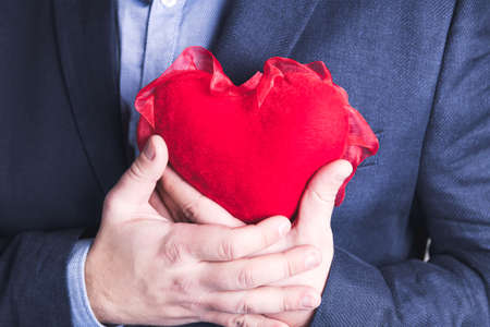 Young elegant man holding a red heart on Valentine's Day. Blue suit.の写真素材