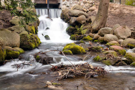 Waterfall on a small river in a park. Moss on a rocks. Tranquil scene.の写真素材