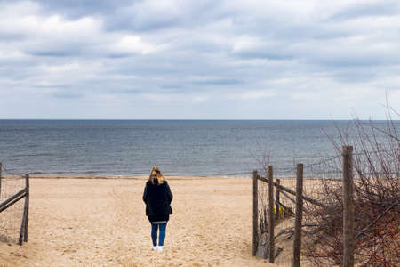 Young woman on a beach looking at the sea with dramatic sky.の写真素材