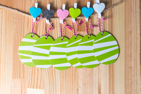 Colorful hearts with greenery easter eggs on a twine. Natural wooden background. Copy space on the...