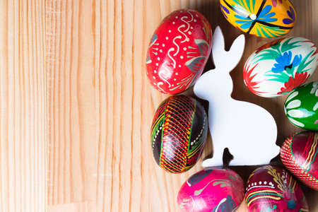 Easter bunny figurine with colorful eggs. Natural wooden background.の写真素材