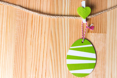 Greenery heart and easter egg on a twine. Natural wooden background. Copy space on the left.の写真素材