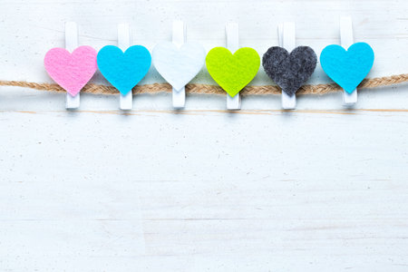 Colorful hearts on a twine on old white natural wooden background. Flat lay top view. Copy space on the bottom.の写真素材