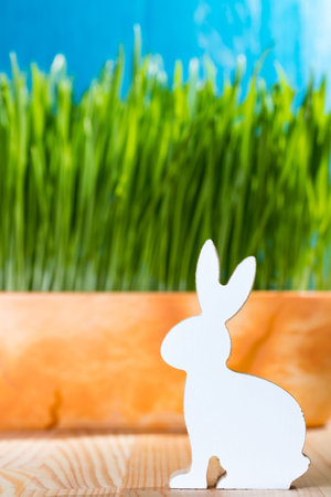 Easter bunny wooden figurine sitting in the grass. Spring time concept.