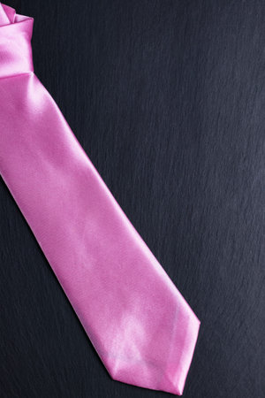 Pink elegant tie on black textured background. Doing business fashion abstract concept. Copy space in the top right corner.の写真素材