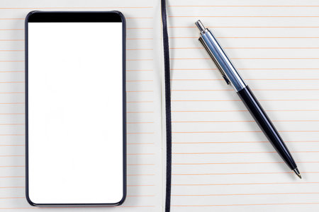 Notepad with elegant pen and bezel less smartphone with blank screen. Ready for mobile application mockup.の写真素材