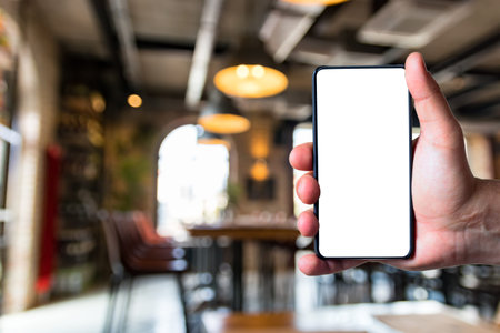 Man using bezel less smart phone with blank screen in a restaurant.の写真素材