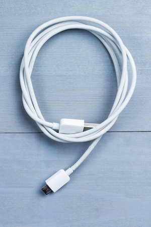 Flatlay of micro usb smart phone power cable on a wooden background. Idea concept.