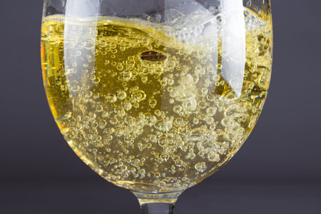 Pouring sparkling white wine into shiny glass against dark background.の写真素材