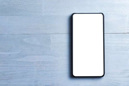 Bezel less smart phone with blank screen on a wooden background. Copy space on the left.の写真素材
