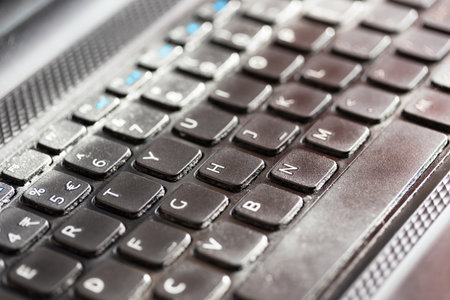 Black worn out laptop computer keyboard keys. Shallow depth of field.