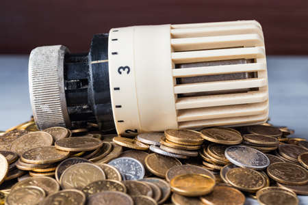 Home heat savings or expenses concept. Radiator regulator on a heap of coins.の写真素材
