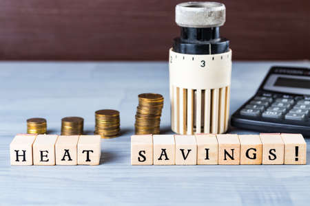 Home heat savings or expenses cost concept. Radiator regulator with coin stacks.の写真素材