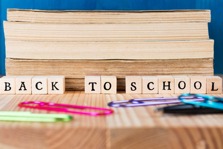 Back to school caption made out of letter tiles. Books on a desk with paper clips.の写真素材