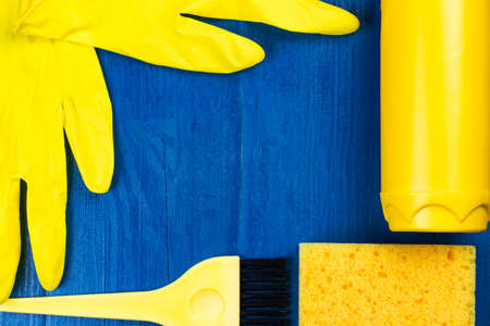 Yellow cleaning supplies on a blue background. Copy space in the center with frame. Flat lay top view.の写真素材