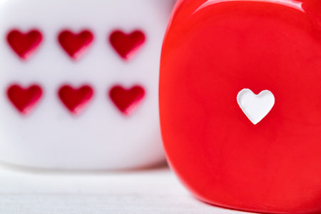 Two red and white Valentines Day heart dice on wooden background. Shallow depth of field.
