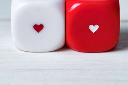 Two red and white Valentines Day heart dice on wooden background. Copy space on the bottom.の写真素材